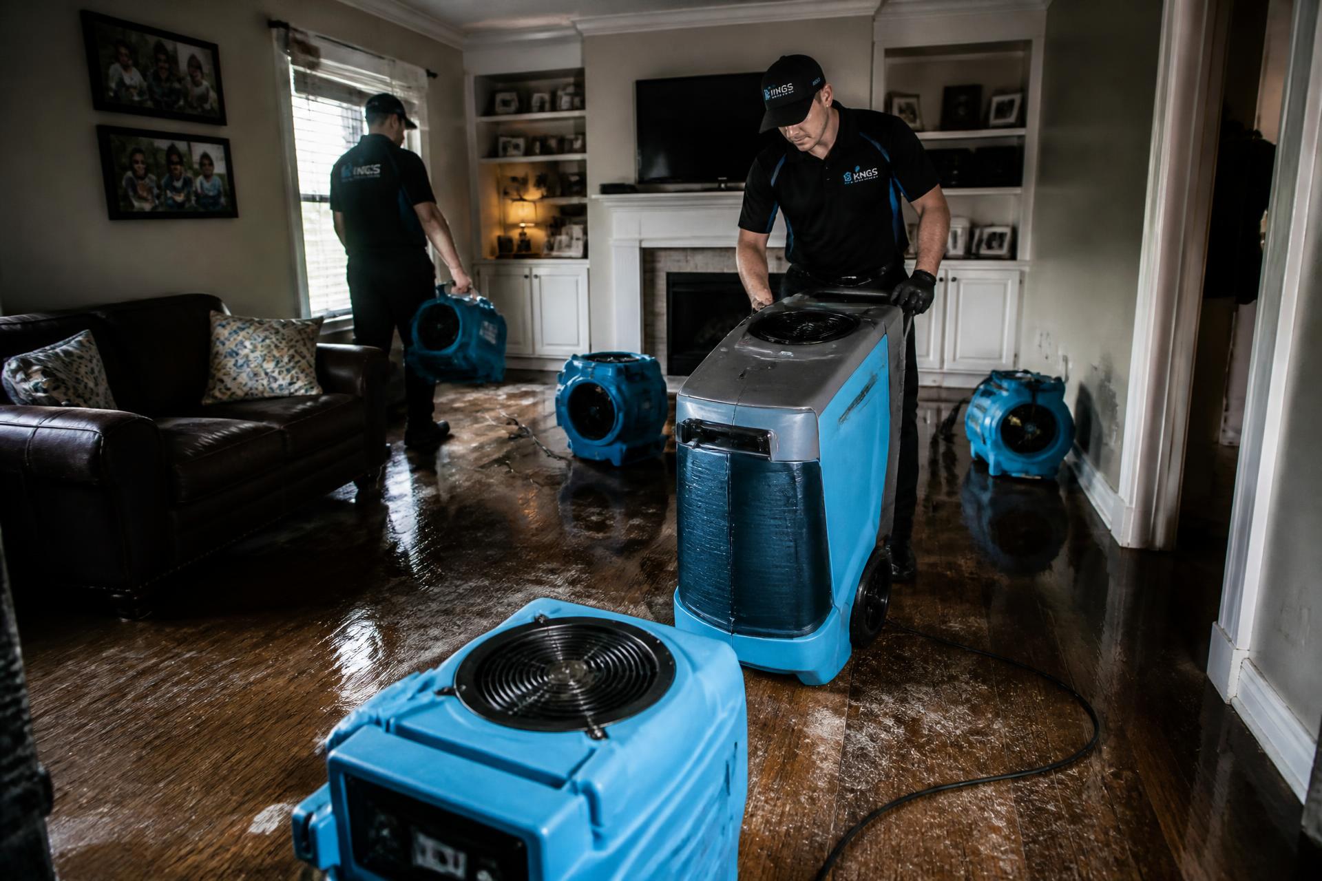 Restoration technicians drying a flooded living room with air movers after water damage